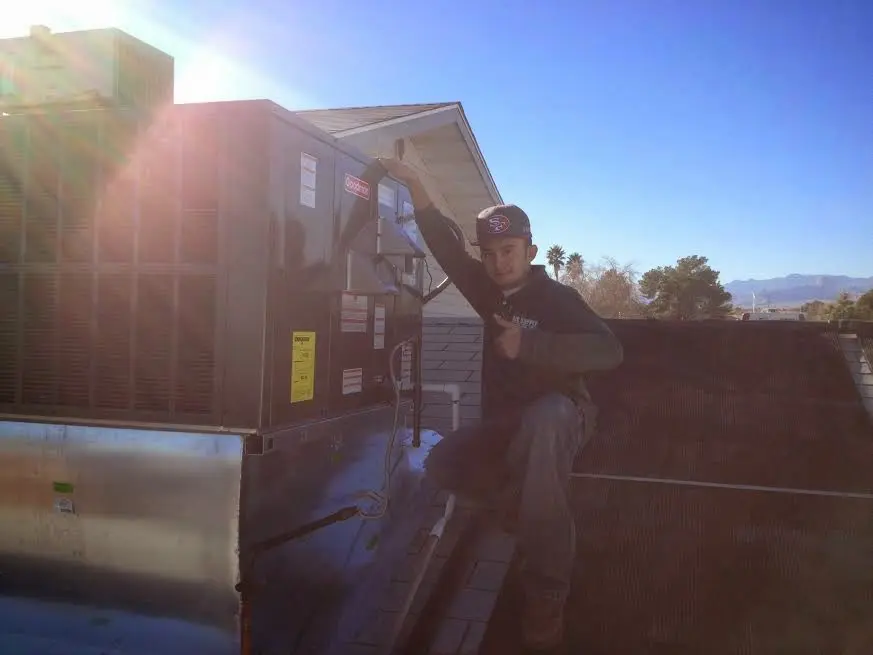 HVAC technician performing Air Duct Cleaning on a rooftop unit in Connersville